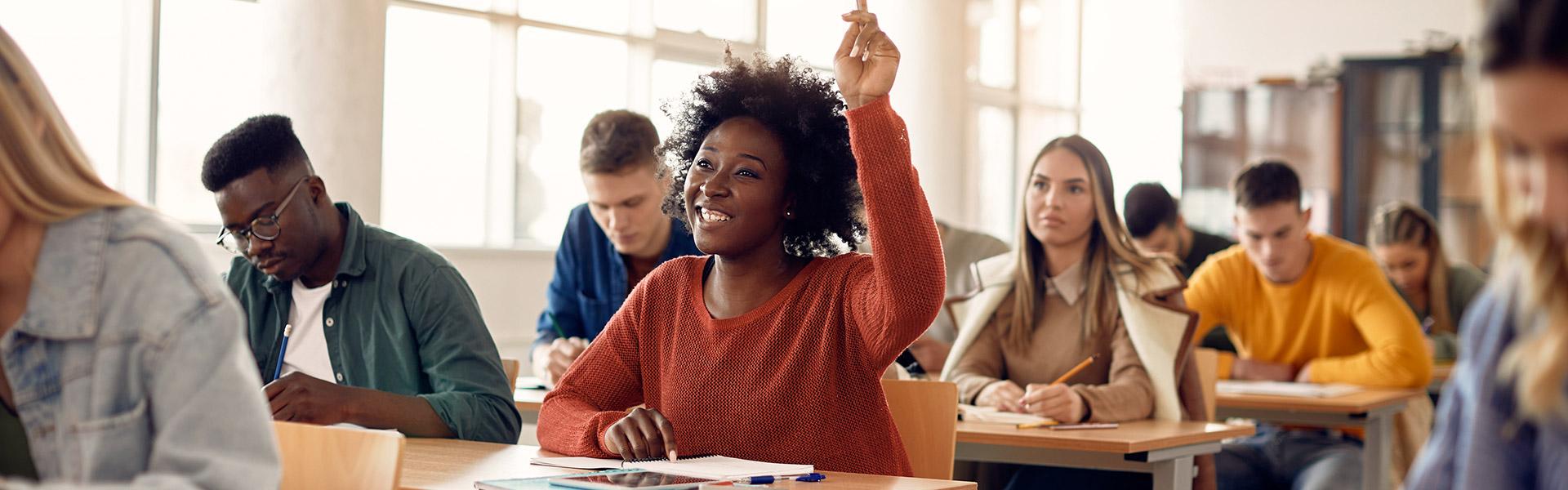 Young smiling African American student holding up right hand in class